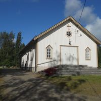 Sideby begravningskapell det vita träkapellet sett från gaveln där dörren är. Kapellet står på en kulle