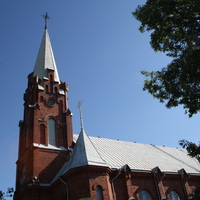 röd tegelkyrka med torn och tak av plåt