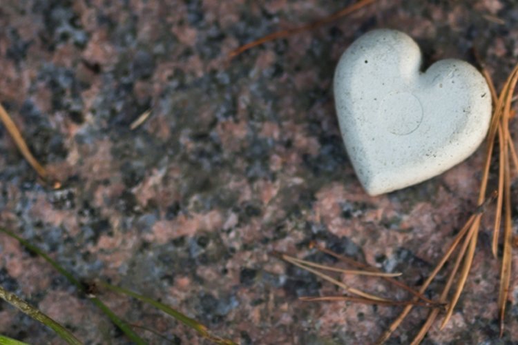 På marken ligger en vit sten formad som ett hjärta.